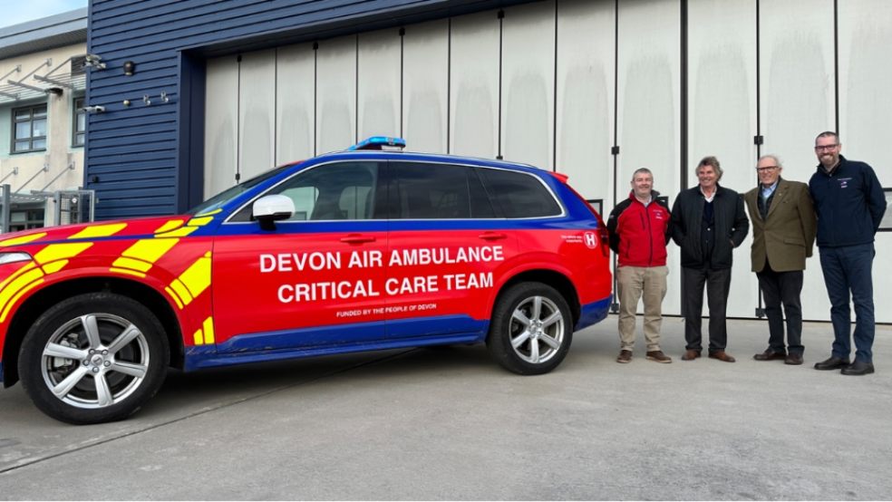 Left to right: Darren Goodwin - Head of Operations DAA Robert Bertram - CEO HELP Appeal, Michael Henriques - Chair of Trustees HELP Appeal and Matthew Bell - Public Engagement Director DAA. Picture of 4 men standing next to a Devon Air Ambulance critical care car